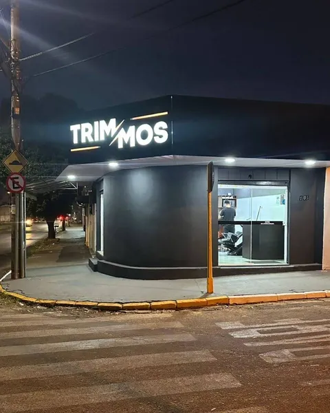 Fachada da Trimmos Barbearia iluminada durante a noite