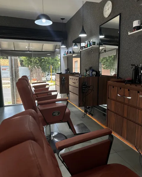 Interior da Trimmos Barbearia com cadeiras de couro marrom enfileiradas, bancadas de madeira, espelhos e entrada de vidro