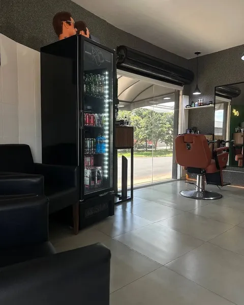 Interior da Trimmos Barbearia com cadeiras, geladeira de bebidas, balcão e entrada envidraçada